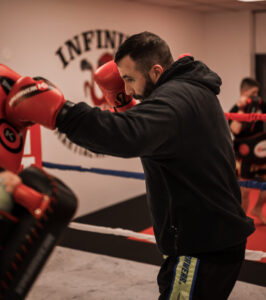 Athletic man training at a boxing gym in Belleville, throwing punches on the mits with his female trainer, focusing on technique and power