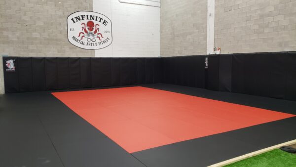 Red and black Brazilian Jiu Jitsu mat space in Belleville's top gym, with black wall mats visible in the background.