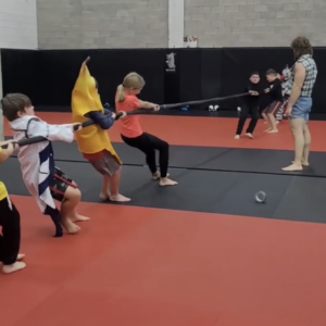 Smiling kids in Muay Thai gear showing teamwork during a thrilling tug-of-war game in class at Infinite Martial Arts & Fitness
