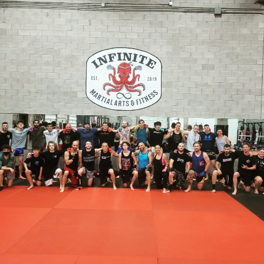 Group of dedicated women and men, after a challenging Muay Thai class at Infinite Martial Arts & Fitness, standing in line, ready to take on their next training session