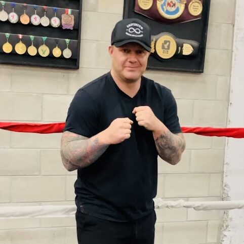 Boxing Coach Blair Crawford stands in the ring at infinite martial arts & Fitness ready to teach new boxers in Belleville