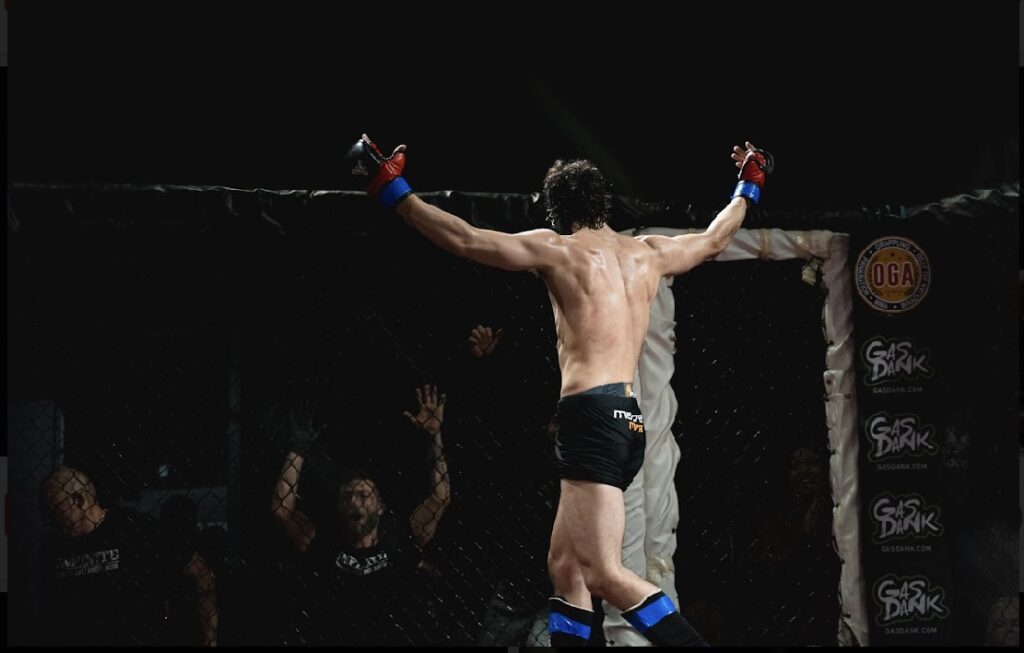 Nick Hatton triumphantly raising his arms in victory inside the cage