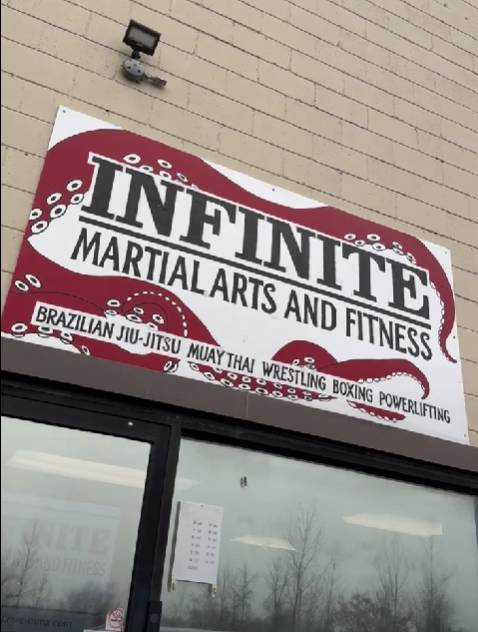Company sign displaying 'Infinite Martial Arts & Fitness' in bold letters, accented with an artistic octopus tentacle, symbolizing strength and versatility.