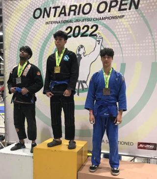 Brazilian Jiu-Jitsu athlete standing on top of a podium, celebrating their victory at a tournament