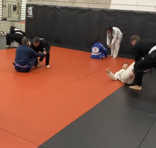 Brazilian Jiu-Jitsu training in a gi on the red and black mats at Infinite Martial Arts and Fitness gym