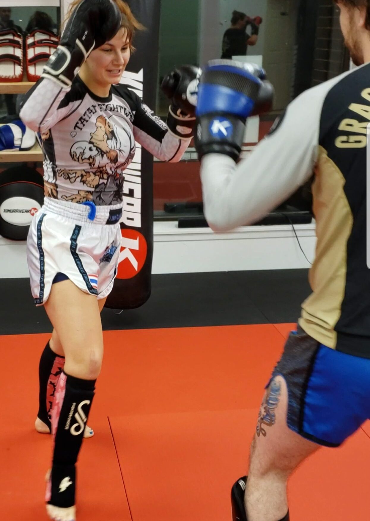 Adorable female Muay Thai fighter training in a small rashguard and traditional Thai shorts at Infinite Martial Arts & Fitness, pushing herself to be the best version of herself.